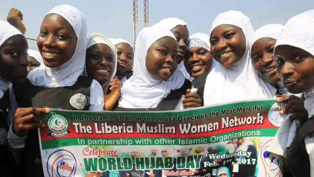 Schoolgirls in hijabs pose for the camera with a post advertising World Hjiab Day in Monrovia, Liberia - Wednesday 1 February 2017