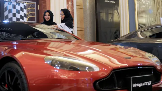 İki Suudi kadın lüks bir arabanın önünde kapıyı açıp arabayı inceliyor.