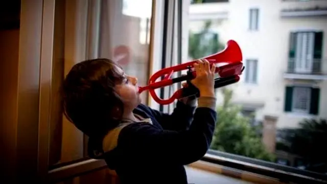 Мальчик у открытого окна играет на трубе