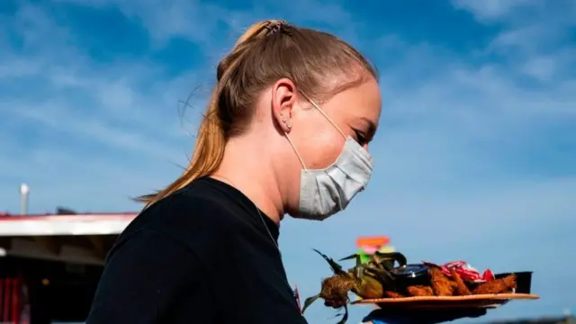戴口罩端着一盘食物的妇女