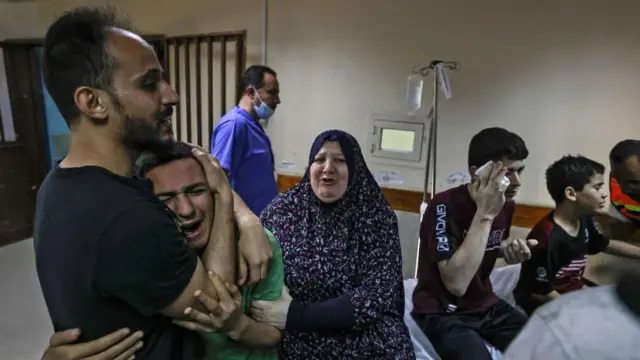 A member of the Abu Dayer family, surrounded by relatives, cries at the Al-Shifa hospital after the death of his father and cousin in an Israeli air strike