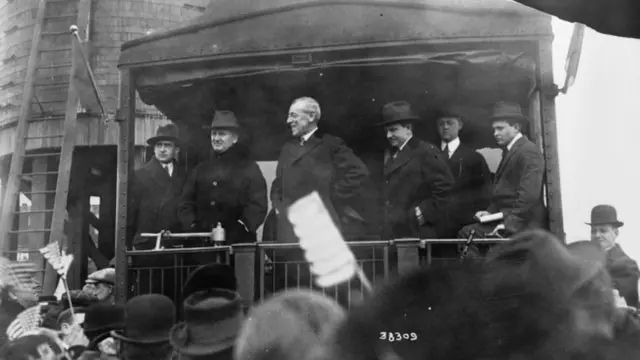 Ông Woodrow Wilson đứng phía sau một con tàu, đang thực hành bài phát biểu