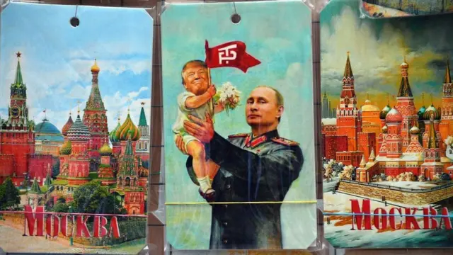 Puesto de venta de souvenirs en donde se ve una tarjeta con Putin elevando a un bebé Trump.