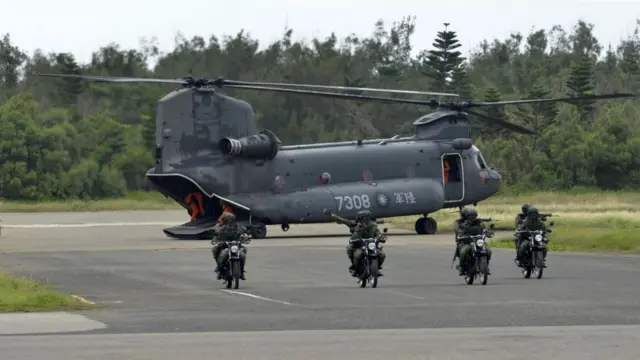 Armed Taiwanese soldiers ride on motorcycles next to a US-made CH-47 helicopter during the 'Han Kuang' (Han Glory) life-fire dril