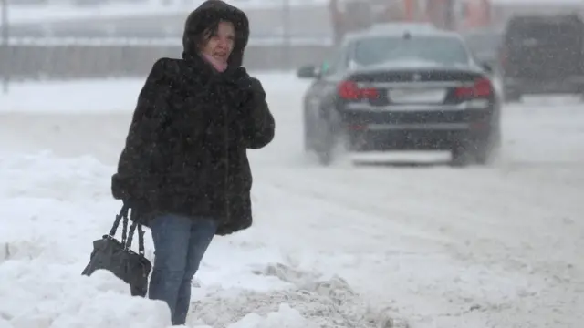 Женщина во время снегопада на одной из улиц города