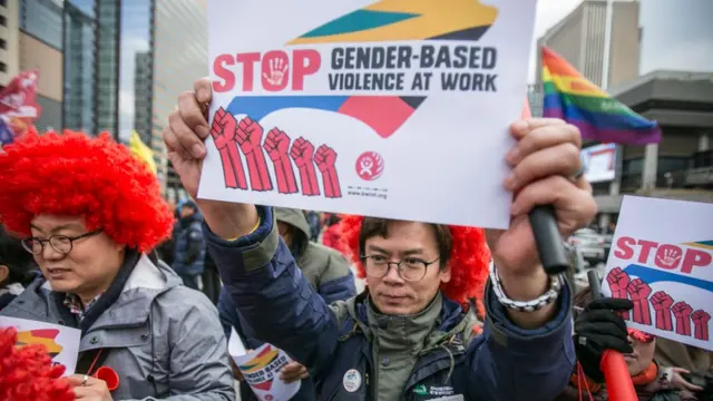 광화문에서 열린 집회에 '직장내 성차별을 중단하자' 라는 종이를 들고 있는 남자