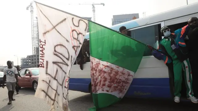 End SARS Protester dey demonstrate from inside bus with flag