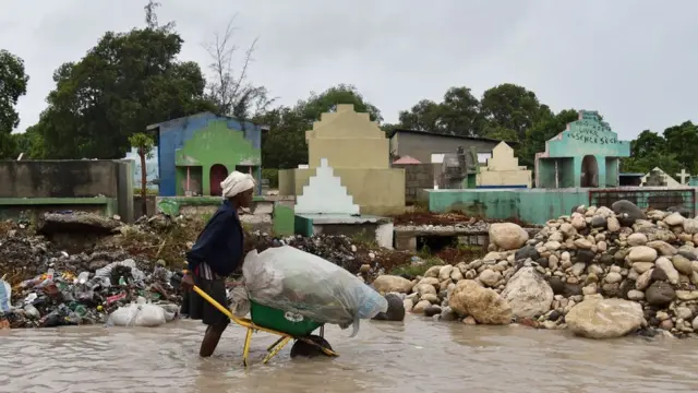 Mwanamke asukuma toroli iliyojaa mali, kwenye mtaa uliofurika maji mjini Port-au-Prince, Haiti, tarehe 4 Oktoba 2016