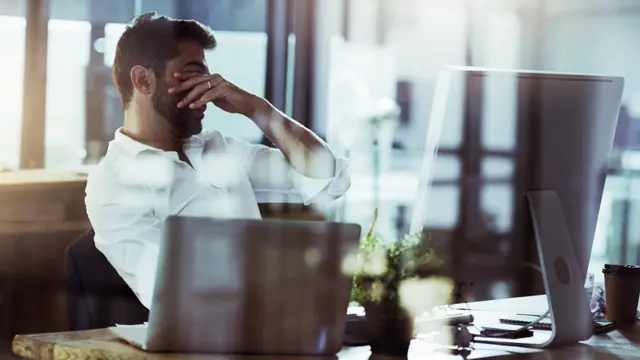 Trabajador cansado frente a una computadora.