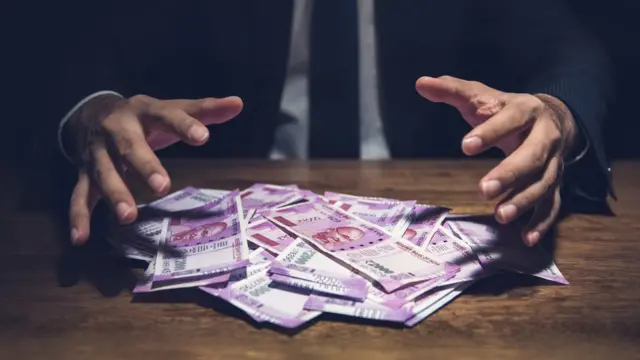 నగదు నోట్లపై ఓ వ్యక్తి చేతులున్న సూచనాత్మక చిత్రం