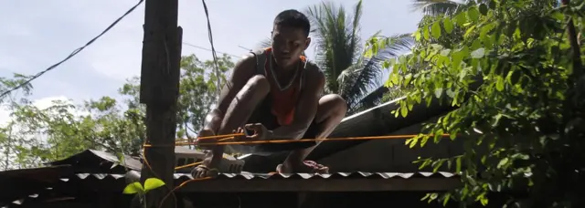 A resident secures the roof of his house to a tree in preparation for super typhoon Mangkhut in Candon City, Ilocos Sur province, north of Manila on September 13, 2018