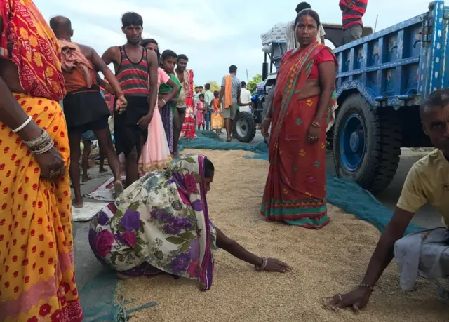 सड़क पर गेहूं सुखाती महिला