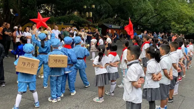 十一前夕，中国贵州有学校组织小学生到校外表演，有小孩穿着红军军服，背着炸药包。