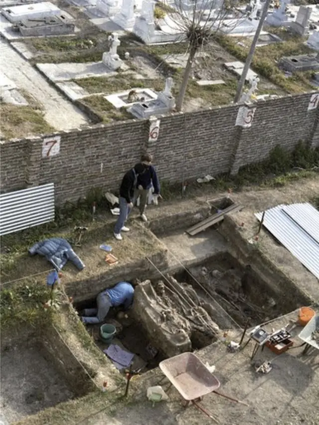 Hombres y mujes excavando en un cementerio.