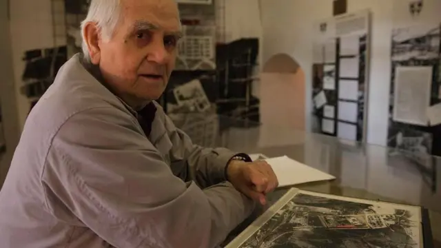 На столе перед Зденеком Мандрголецем - спутниковые фотографии лагеря, куда его поместили после ареста в 1953 году