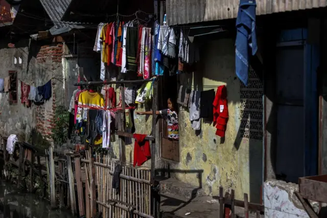 Seorang anak tengah melihat pakaian yang sedang di jemur di permukiman kumuh di Jakarta.