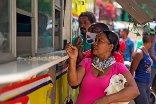 Personas hacen fila para recibir sus comidas en un camión de alimentos del gobierno en el barrio El Dique, en Santo Domingo.