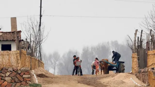 2017년 4월 16일 북한 신의주 압록강변 도로에서 한 북한 남성과 여러 명의 어린이들이 자전거를 타며 노는 모 습 