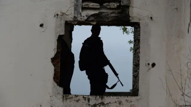 Imagem da silhueta de um policial armado.