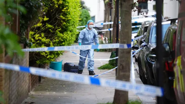 火災現場付近を調べる捜査員