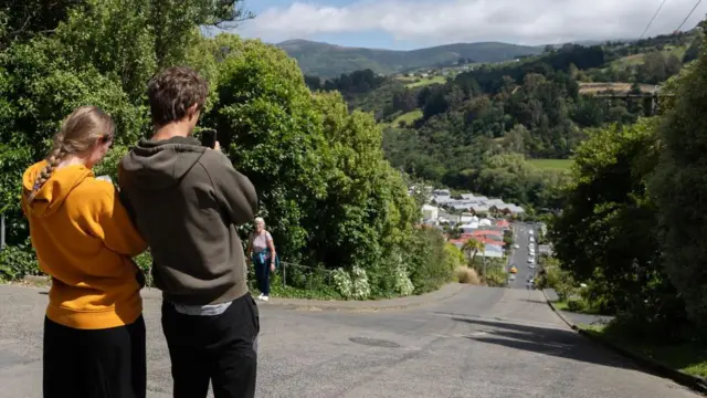 Visitantes tiram fotos em rua mais íngreme do mundo, em Dunedin, na Nova Zelândia, em 21 de janeiro de 2025