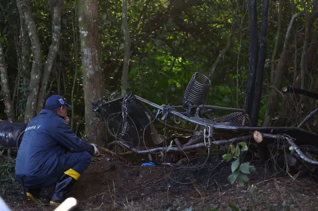 Integrante do Centro de Investigação e Prevenção de Acidentes Aeronáuticos (CENIPA) caminha ao lado dos destroços de um balão de ar quente que pegou fogo e caiu com 21 pessoas a bordo, em Praia Grande