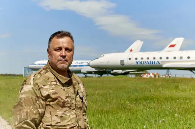 Чоловік стоїть в полі на фоні літаків