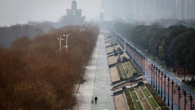 Two people walk down an empty street in Wuhan, 27 January 2020