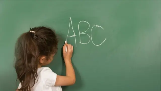 Imagem de banco de imagem de criança escrevendo em uma lousa