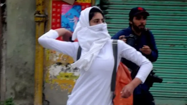 নিরাপত্তা বাহিনীর দিকে পাথর ছুঁড়ছেন এক তরুণী