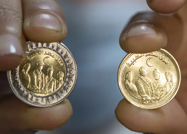 A clerk shows two new Egyptian coins.