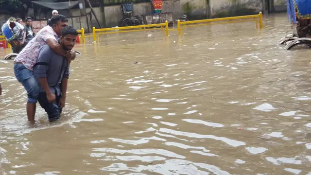 ঢাকার গ্রিনরোড, একজনের পিঠে চড়ে আরেক ব্যক্তি রাস্তা পার হচ্ছে।