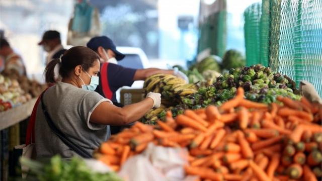 A woman wearing a protective mask picks vegetables in a street market during the nationwide quarantine in response to the spread of coronavirus disease (COVID-19) in Caracas, Venezuela March 31, 2020.
