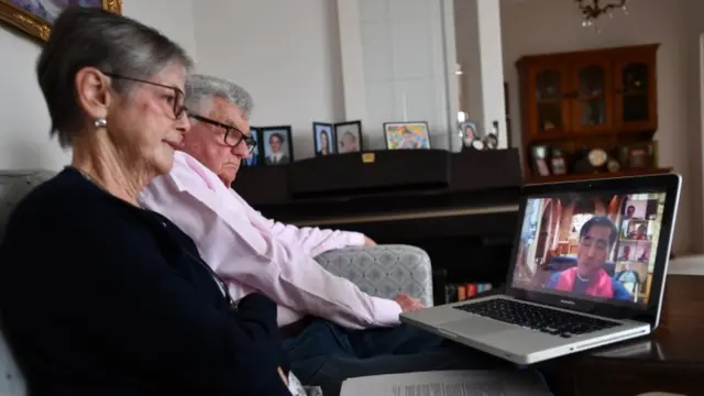 Pareja en Adelaida, Australia, siguen la misa por internet este viernes.