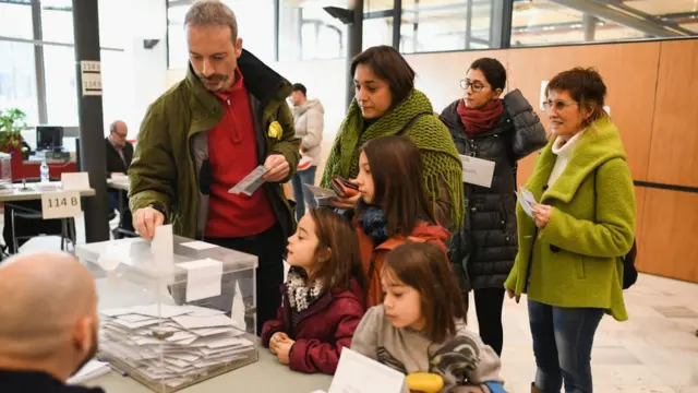 ఓటేస్తున్న కాటలోనియా వాసి. ఆసక్తిగా చూస్తున్న కుటుంబం