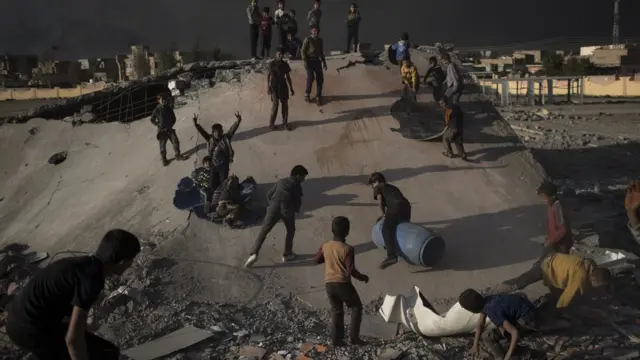 Crianças brincam de escorrega com destroços