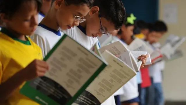 Crianças lendo livros didáticos