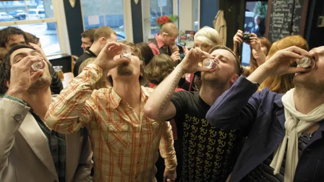 Cuatro hombres toman tequila en un bar.