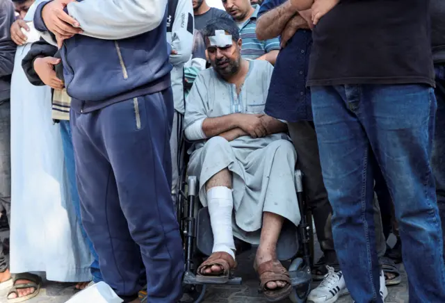 مشيعون بينهم مصاب على كرسي متحرك يصلون الجنازة على من قُتِلوا في غارات إسرائيلية، في مستشفى شهداء الأقصى، في دير البلح في وسط قطاع غزة، 21 مايو/ أيار 2025.