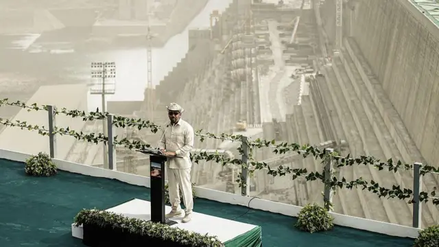 En una pequeña tarima con un atril, Abiy Ahmed habla. A sus espaldas, se ve una enorme infraestructura hidroeléctrica.
