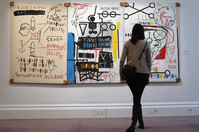 LONDON, ENGLAND - JANUARY 31: A visitor stands in front of a painting by Jean-Michel Basquiat entitled 'Five Fish Species,' on January 31, 2013 in London, England. The triptych painting is estimated to sell for between £4.25-6.25 Million GBP when it goes on sale at the 'Contemporary Art' evening sale at Sotheby's auction house on February 5, 2013. (Photo by Dan Kitwood/Getty Images)