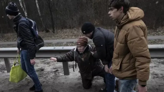 Deux jeunes hommes aident un homme âgé à se relever