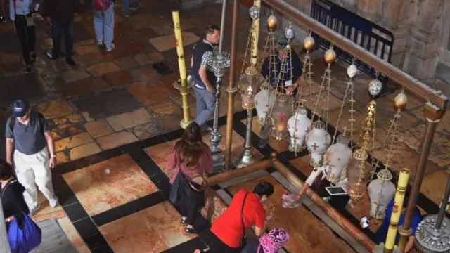 游客和朝圣者亲吻涂膏礼之石，他们相信耶稣在葬礼前正是在这块石头上完成清洗等仪式的