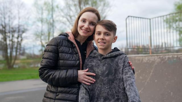 Daniel e a mãe Kateryna lado a lado em frente a uma pista de skate