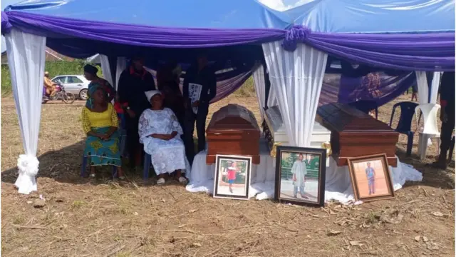 Okechukwu widow siddon close to di coffins of her husband and two children during dia burial