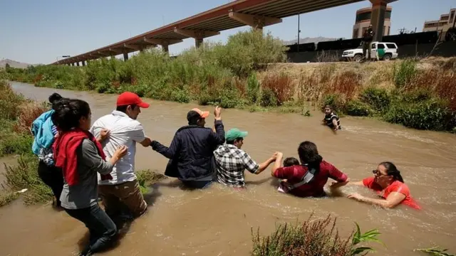 Migrantes cruzando un río fronterizo