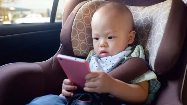 Criança pequena olha para um celular