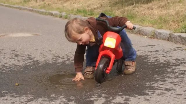 Niño juega con un charco de agua