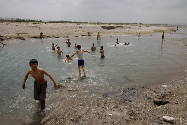 Dečaci odeveni u tradicionalne šalvar kamize kupaju se u reci Hari