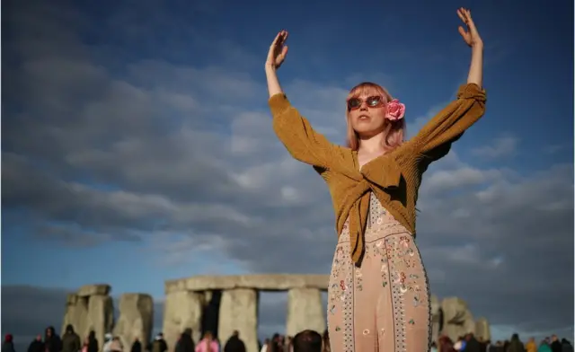 Жінка зустрічає сонце біля Стоунхенджу